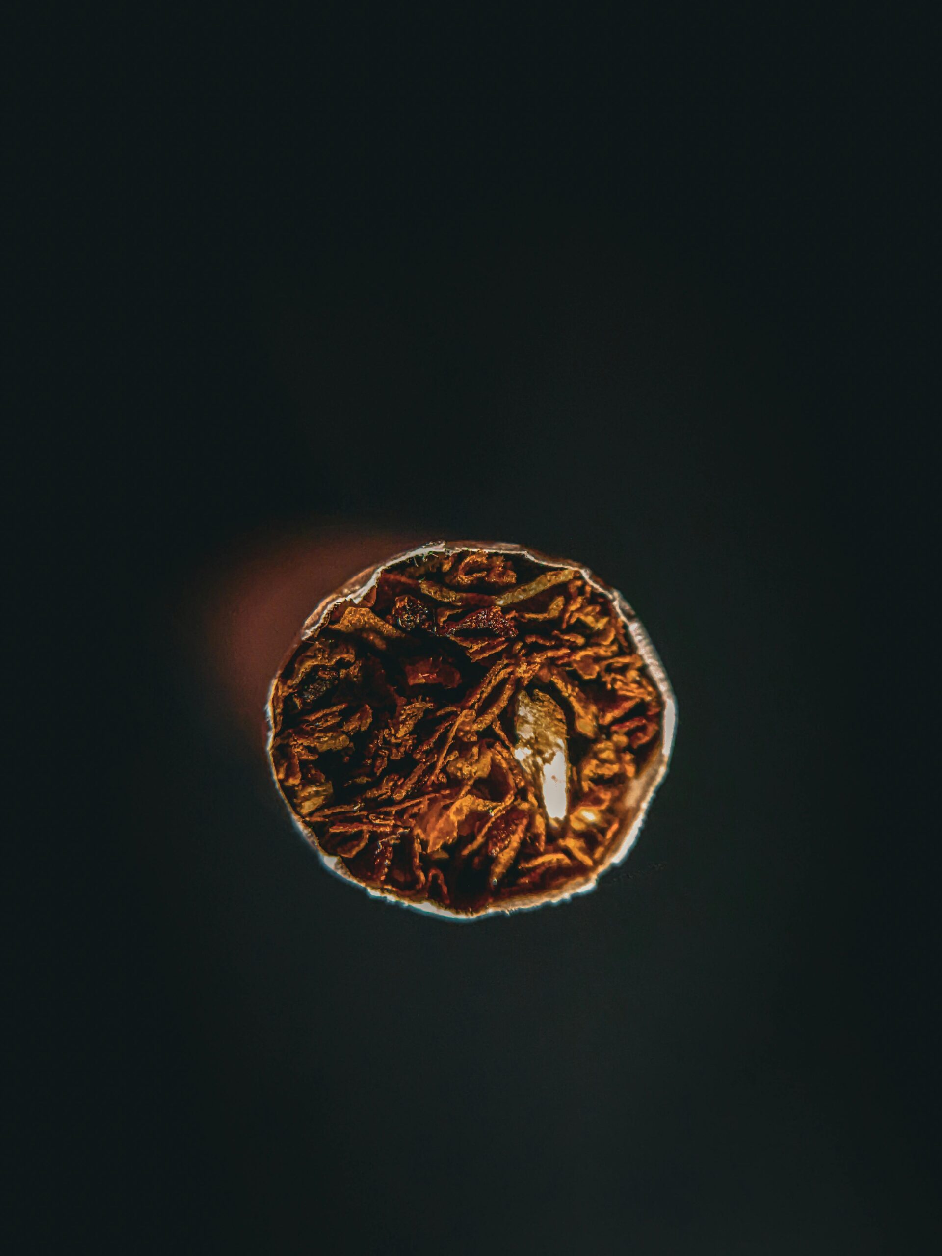 Macro shot of a cigarette's lit end against a dark background.